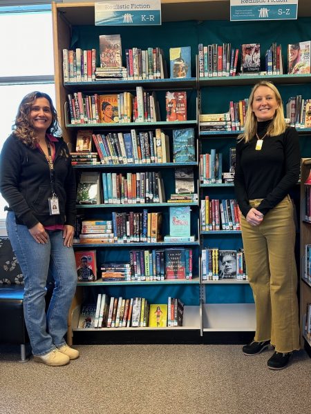 Kat Croasdale and Vanessa Tampoa pose in front of a library shelf.