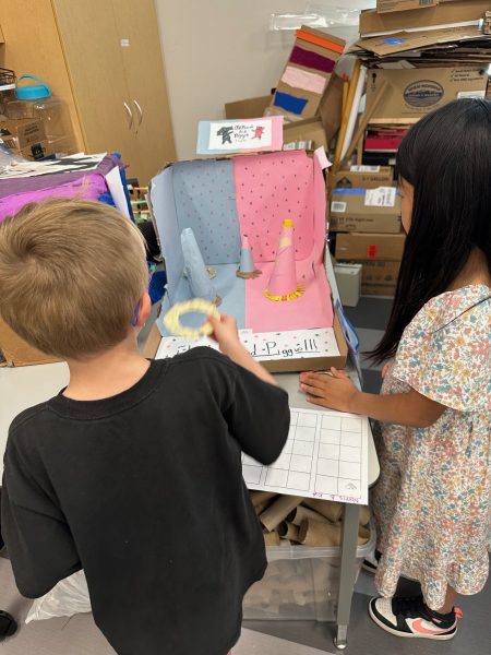 A kindergarten student tosses a ring at three cones, trying to score points while playing the Elephant and Piggie arcade game.