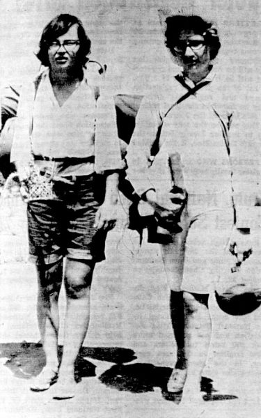 Two teenage girls carry camping equipment