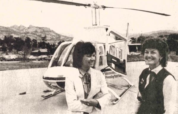 A hospital administrator and flight nurse stand in front of a helicopter