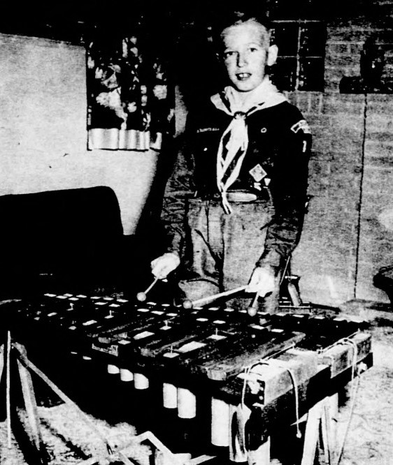 A boy in a scouting uniform plays the marimba.
