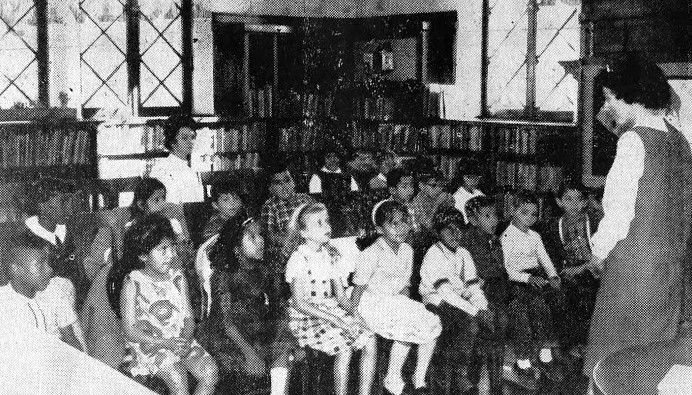 A class of school children listen to a librarian.