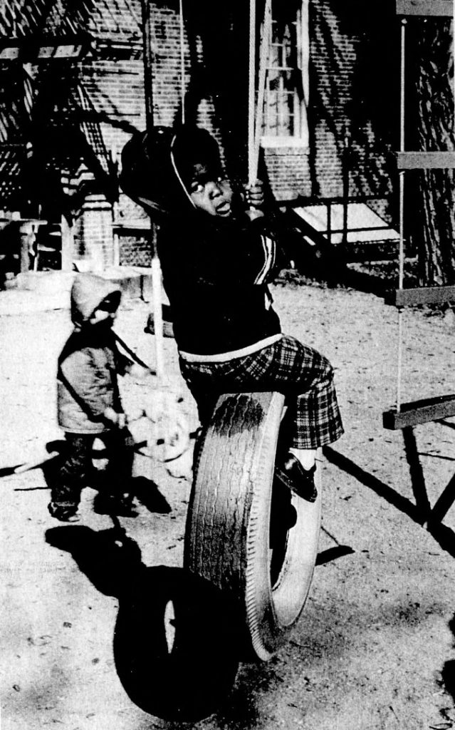 A little boy swings on a tire swing.
