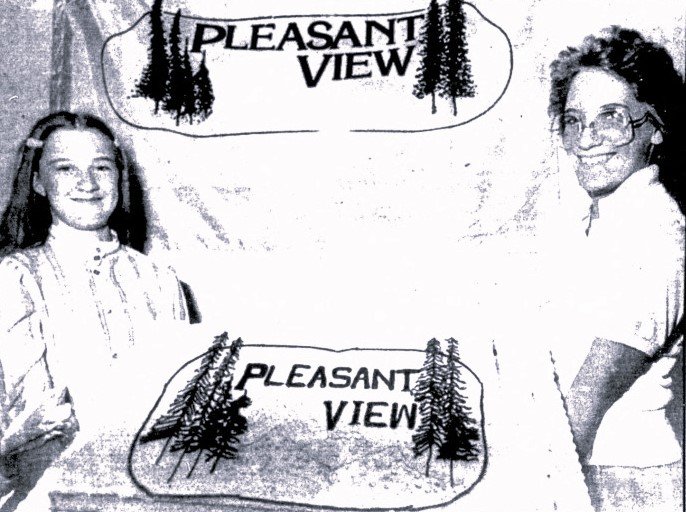 A girl and a woman hold up a sheet cake bearing the text "Pleasant View"