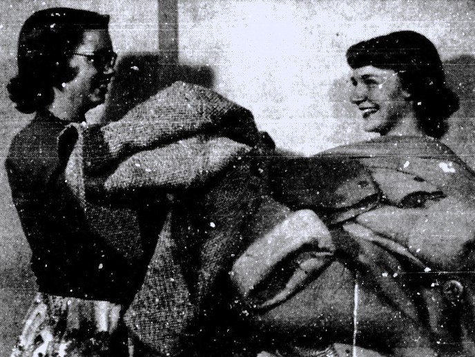 Two young women collect coats to donate in the aftermath of the Korean War.