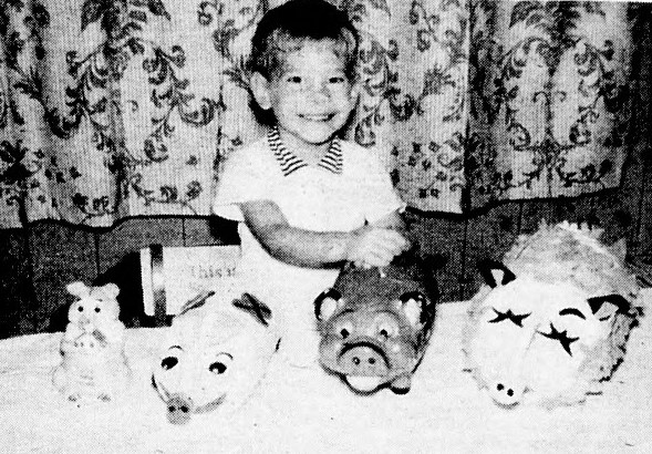 A young boy lines up 4 piggy banks.