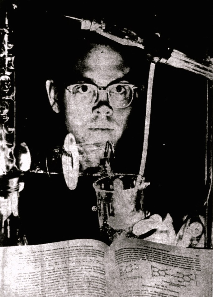 A high school boy pours liquid from one beaker into another.