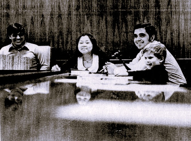 A young boy holds the gavel at a university student council meeting.