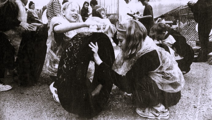 A group of school children clean off tires in the rain.