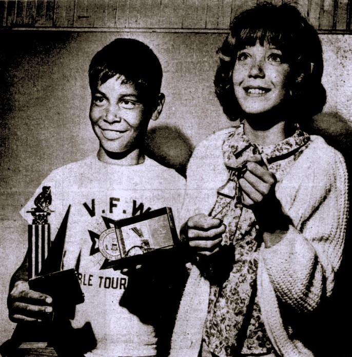 A boy and girl pose with their trophies.