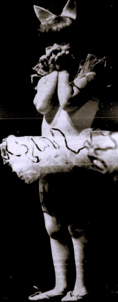 A young girl wearing a ballet costume holds her hands to her face.
