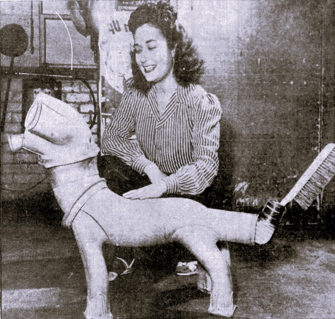 A woman poses with a dog made from machine parts