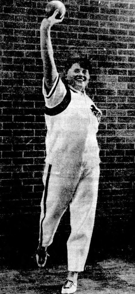 A young woman poses with a shot put
