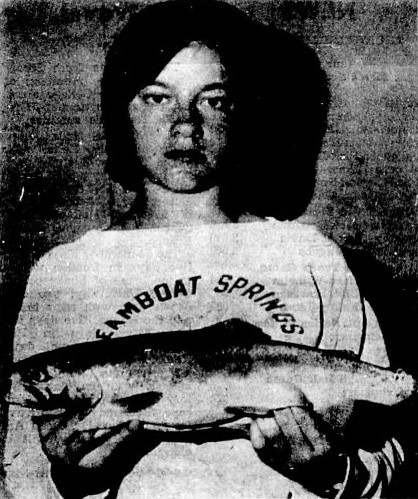 A girl holds up the trout she caught.