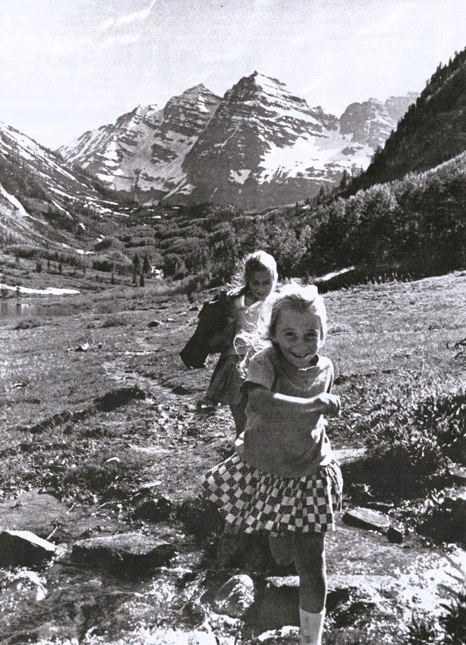 Two girls run on a trail in front of the Maroon Bells.