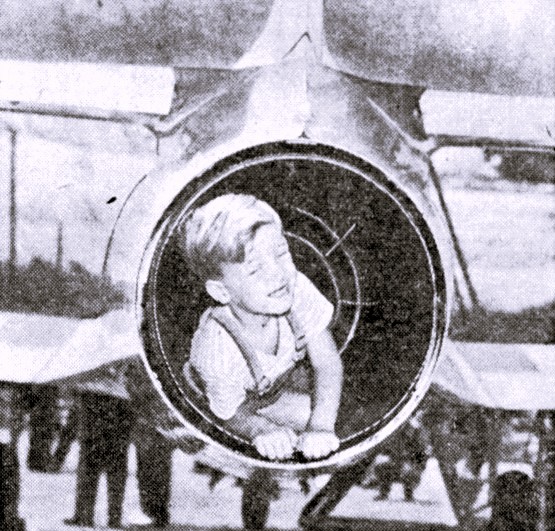 A little boy lays in a jet engine turbine.