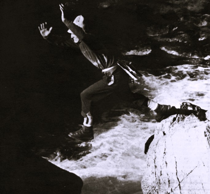A man jumps over a river from rock to rock.