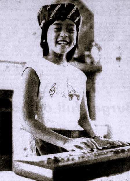 A girl wearing a cap plays a keyboard.