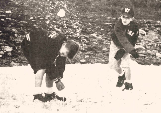 A boy dodges a snowball thrown by his brother.