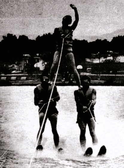 3 teenage water skiers perform a stunt.