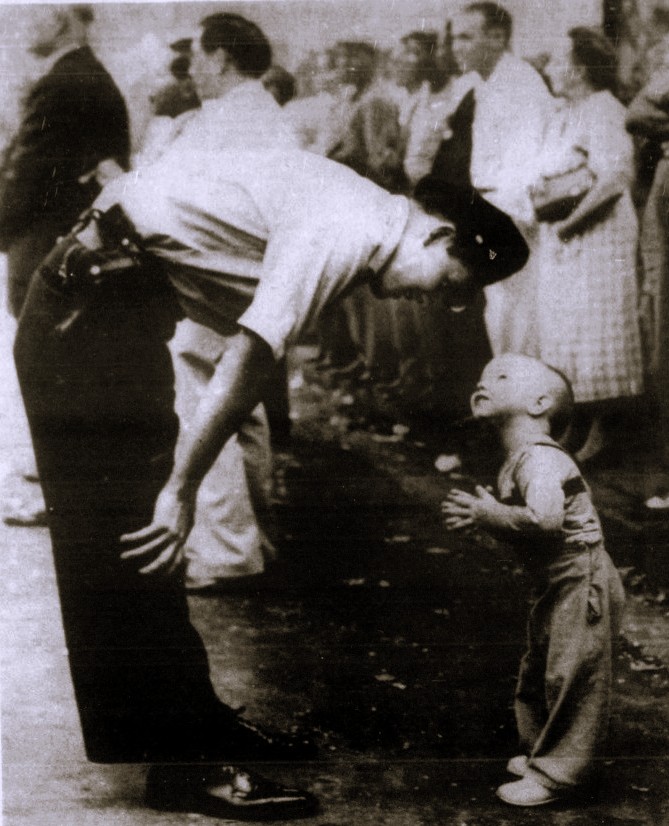 A police officer bends down to talk to a young boy.