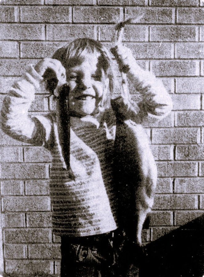 A young girl holds up a large fish that she caught and a small fish that her father caught.