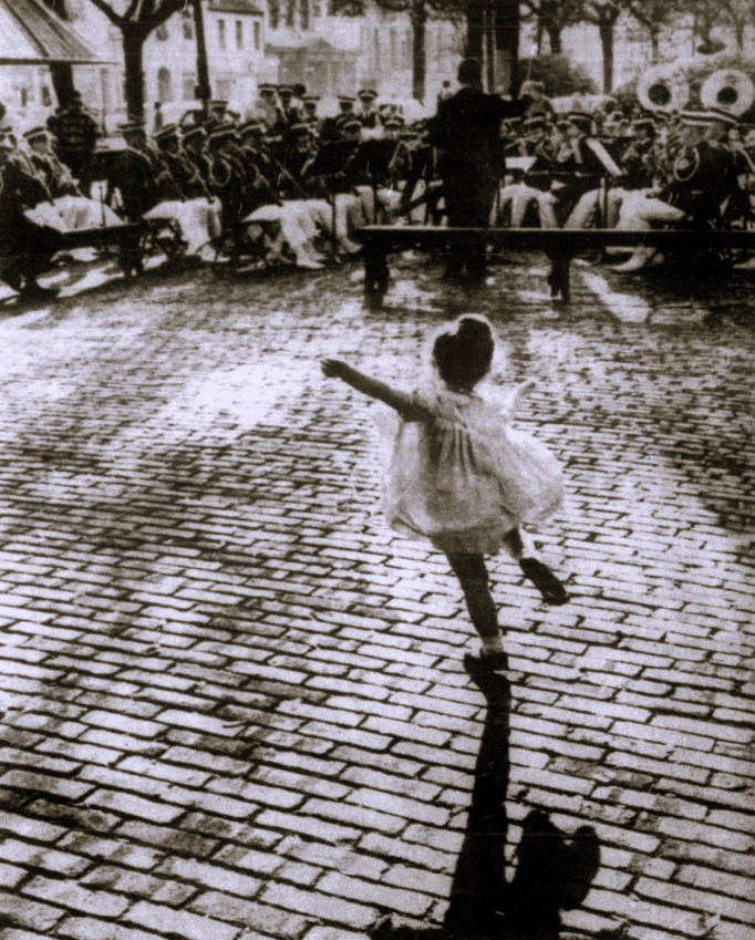 A young girl dances in front of a brass band.