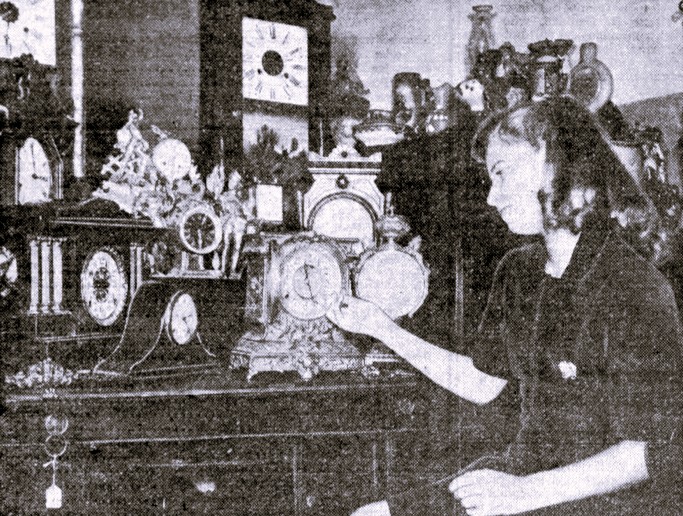 A young woman is surrounded by clocks.