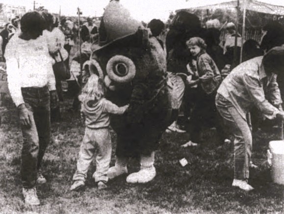 A young girl hugs a Woodsy the Owl mascot.