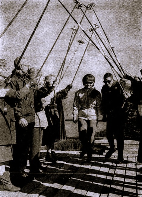 A newly married couple is saluted by guests holding ski poles.