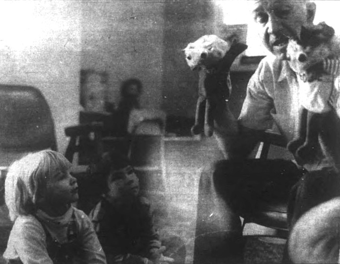 A man gives a puppet show to two young children.