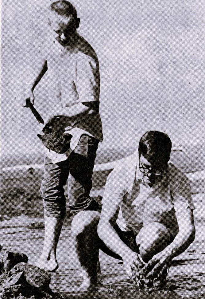 Two high school boys build a sand castle.