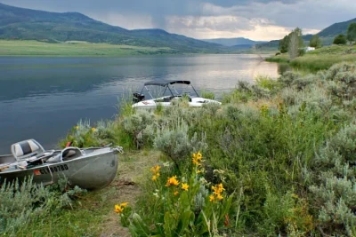 Two small boats sit on a grassy bank next to the Stagecoach Reservoir.