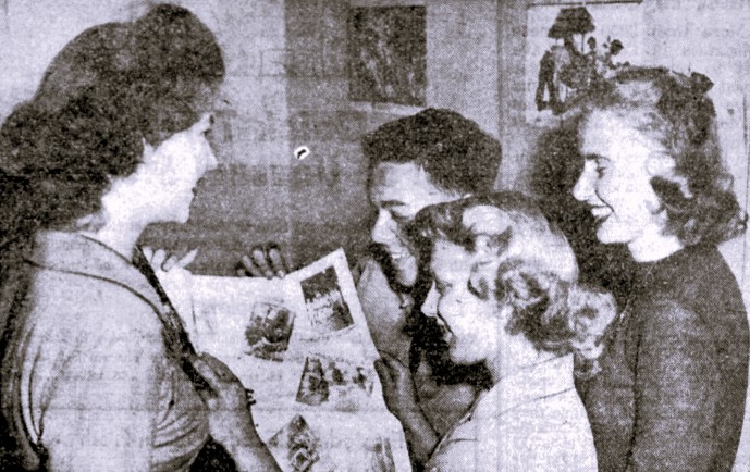 Four high school journalists read a newspaper proof.