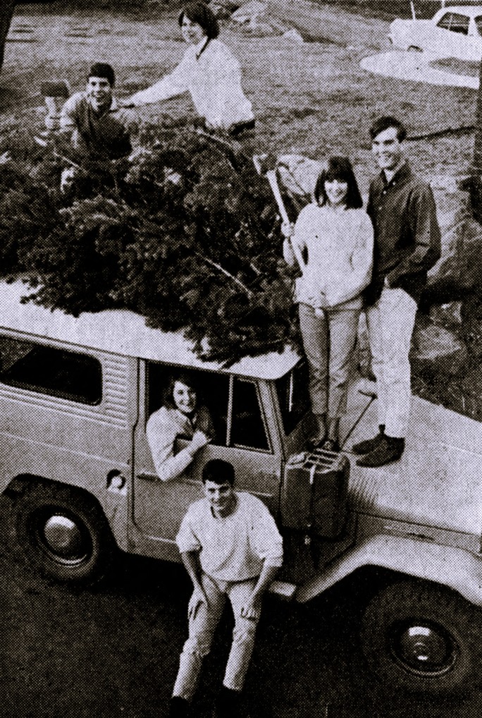 6 high school students pose with the trees they cut and loaded on a Jeep.