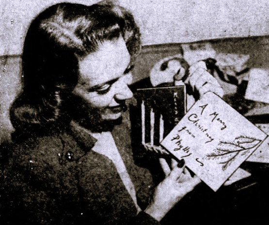 A woman holds an engraved metal Christmas card.
