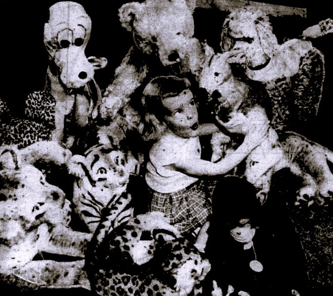 A girl sits amidst many stuffed animals.