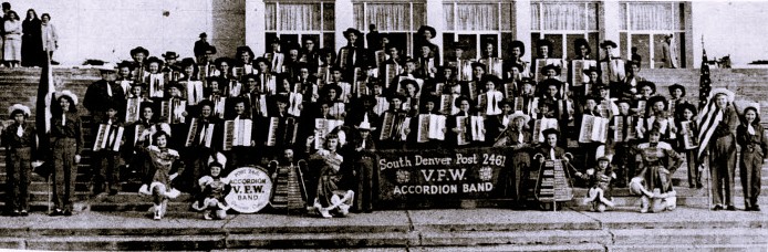 A large accordion band poses on the steps of a building.