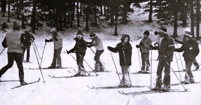 A group of boys follow a ski instructor.