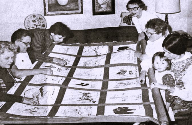 Six women and one girl work on a quilt commemorating the U.S. Bicentennial.