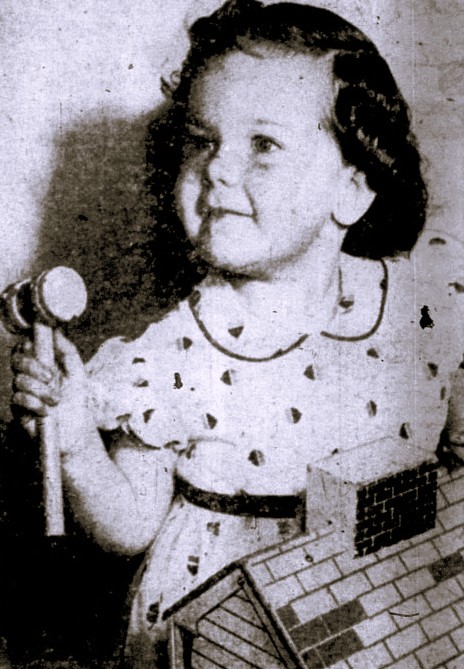 A young girl holds a toy hammer.