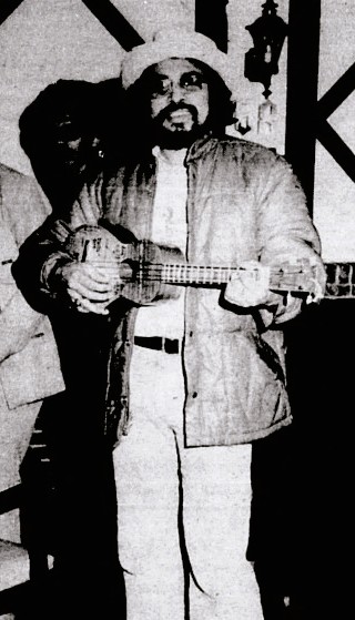 A man wearing a hat plays the ukulele.