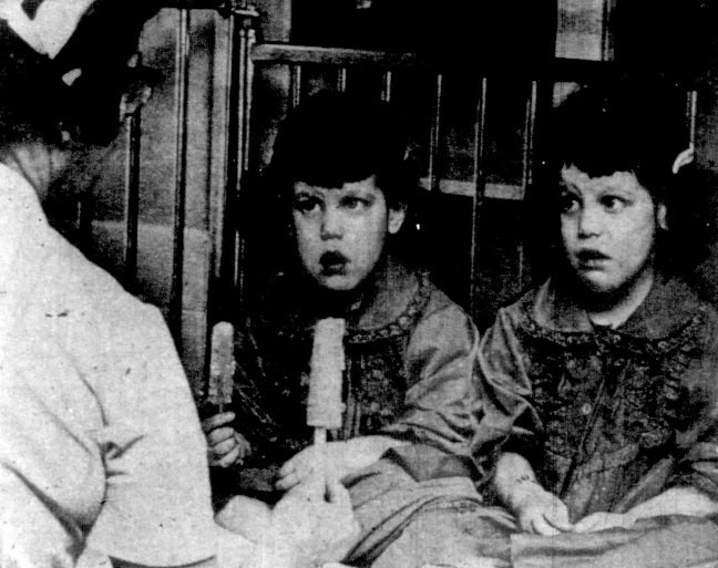 A nurse offers popsicles to twin girls.