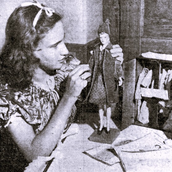 A girl shows the doll fashion that she sewed.