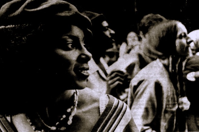 A woman in a crowd watches a Mardi Gras parade.