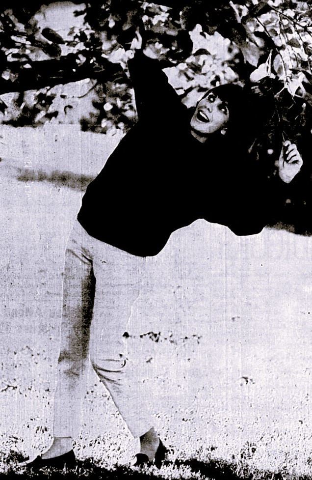 A young woman poses under a tree.