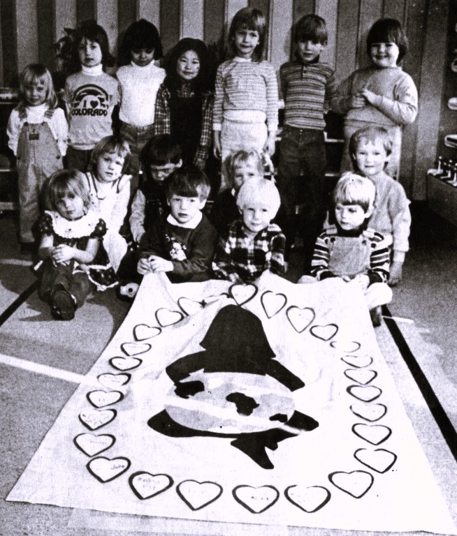 A preschool poses with the banner they decorated.