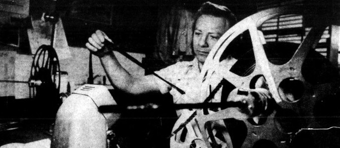 A man examines reel-to-reel film.