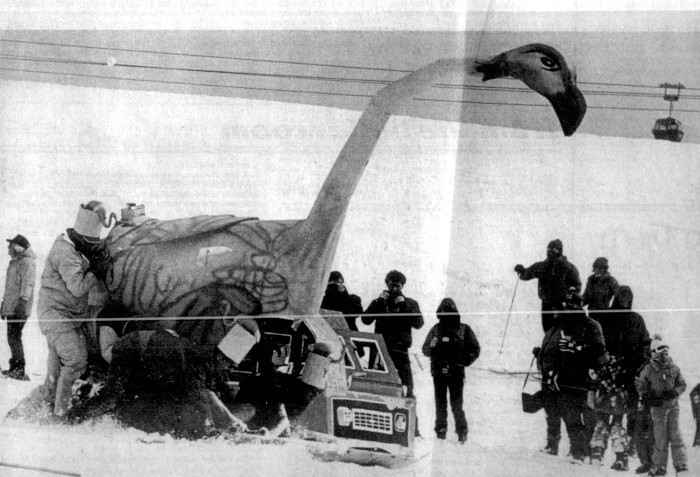 A group of skiers surround a snow vehicle decorated as a flamingo.