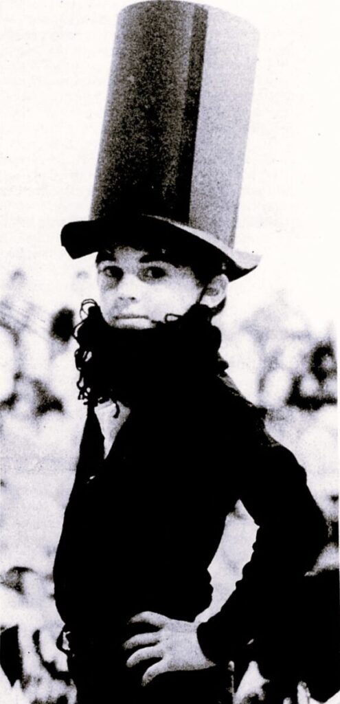 A boy is dressed as Abraham Lincoln in a top hat and beard.